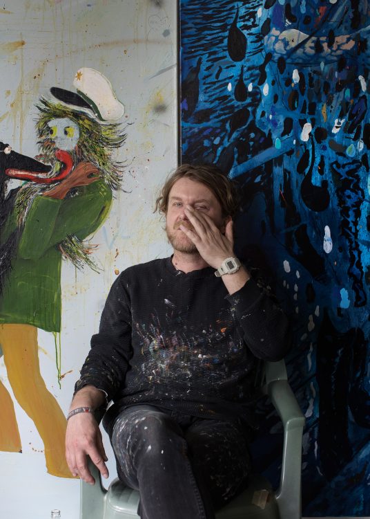 Moritz Schleime in his Berlin Studio in front of two of his paintings.