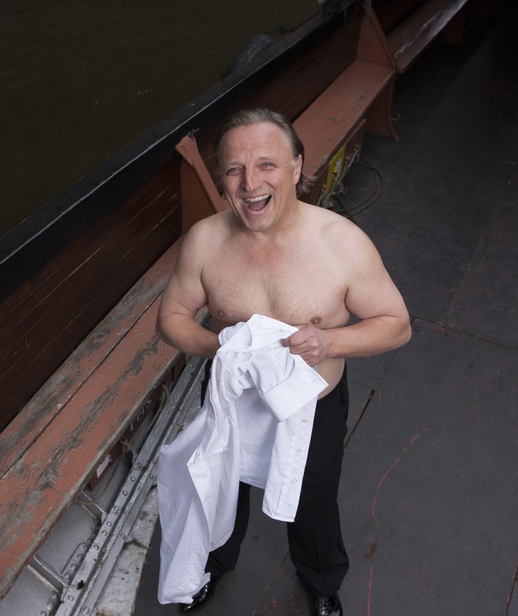 Portrait of German actor Axel Prahl smiling while getting dressed on a boat.