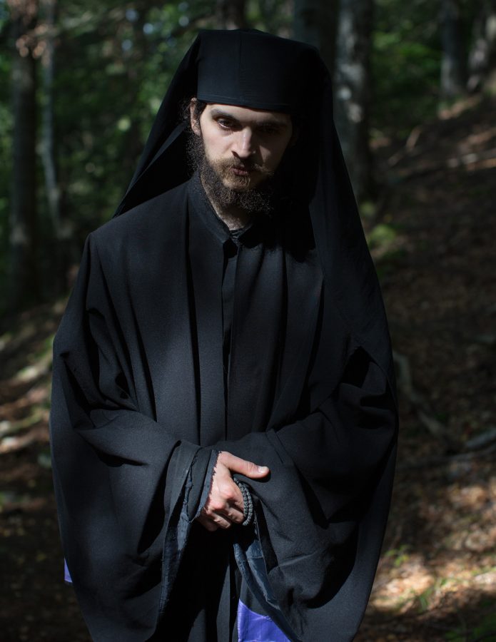 Eastern orthodox hieromonk wearing a black robe in a forest.