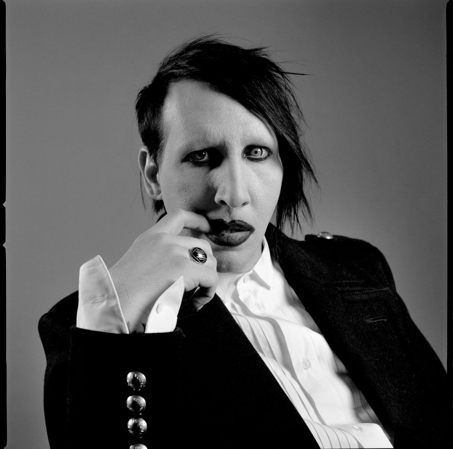 Marilyn Manson in a suit wearing make-up and a ring.