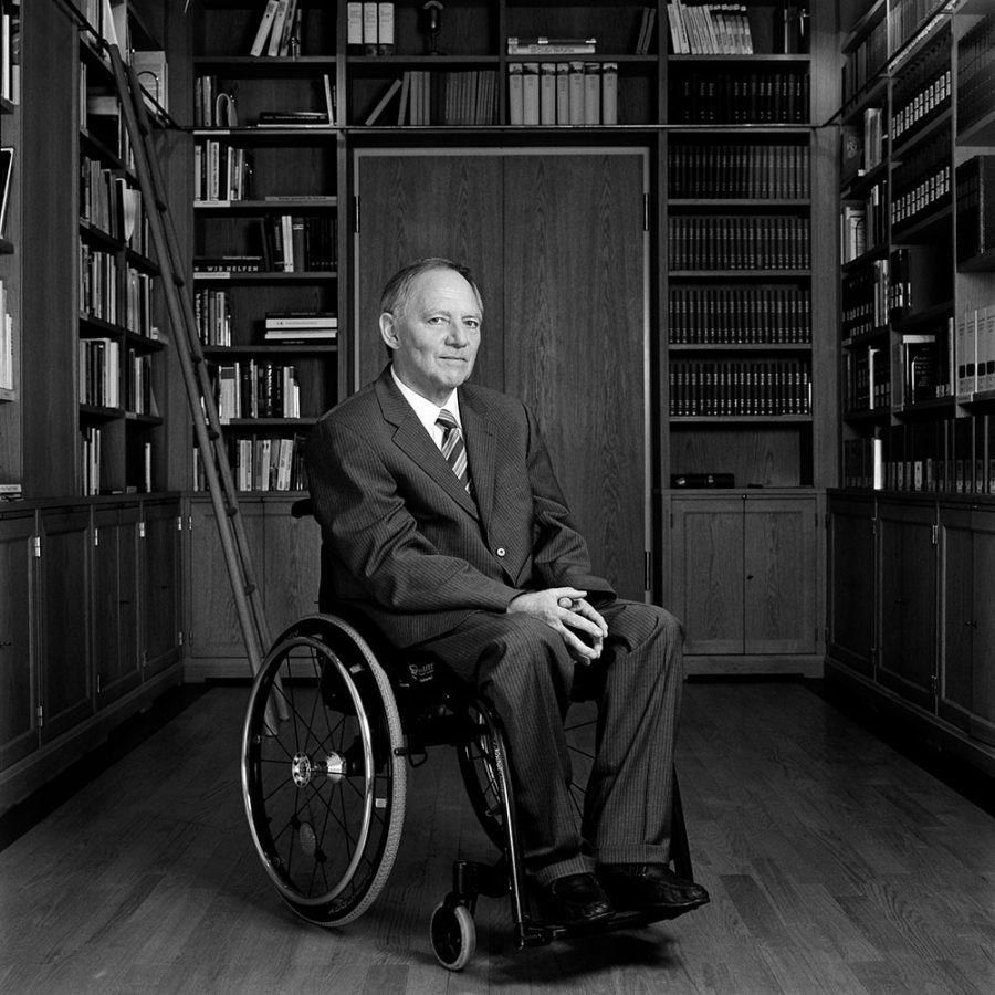 Wolfgang Schäuble posing for a picture in a small wooden library.