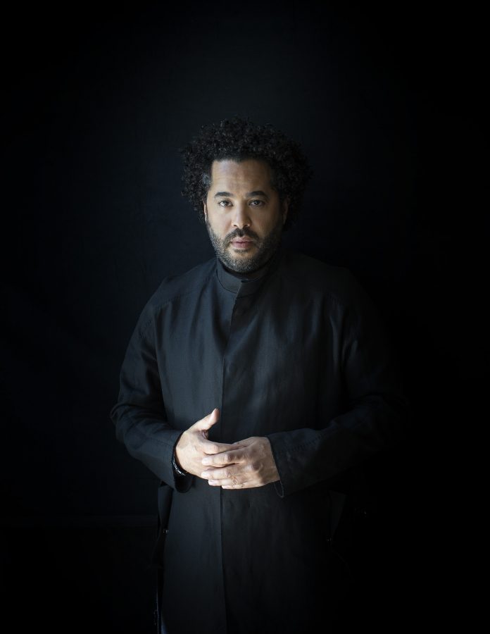 Studio portrait of the musician Adel Tawil against a black background.