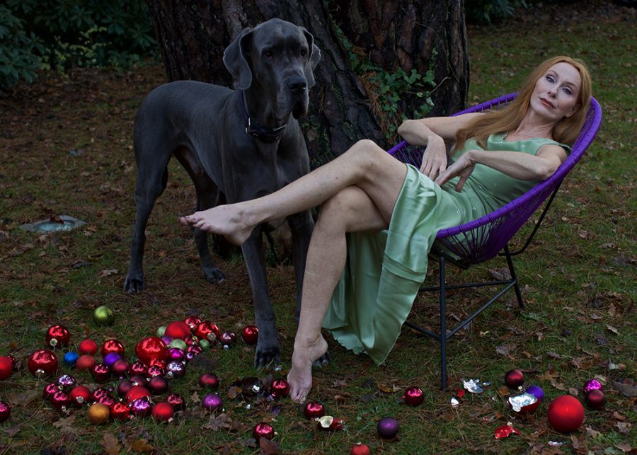 Andrea Sawatzki sitting in an Acapulco Chair in a garden with a large sized dog.