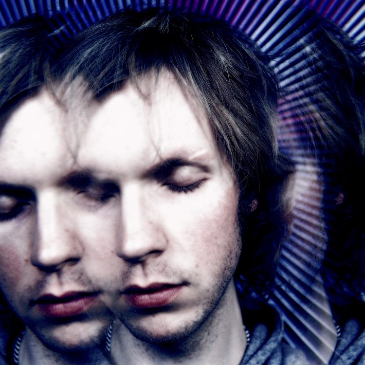 Close-up portrait of musician Beck having his eyes closed against an abstract blue background.