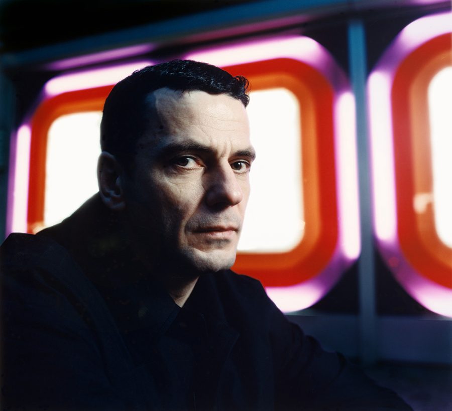 Director Christian Petzold with red and purple neon lights in the background.