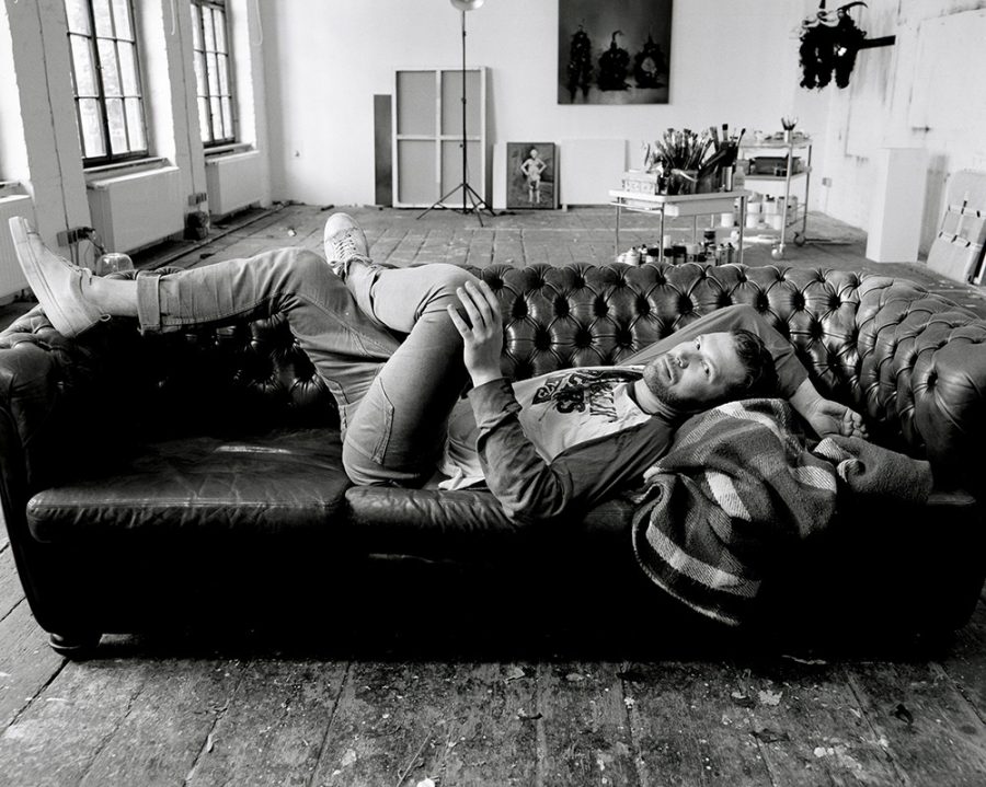 Daniel Kannenberg lying on a black couch in a loft atelier.