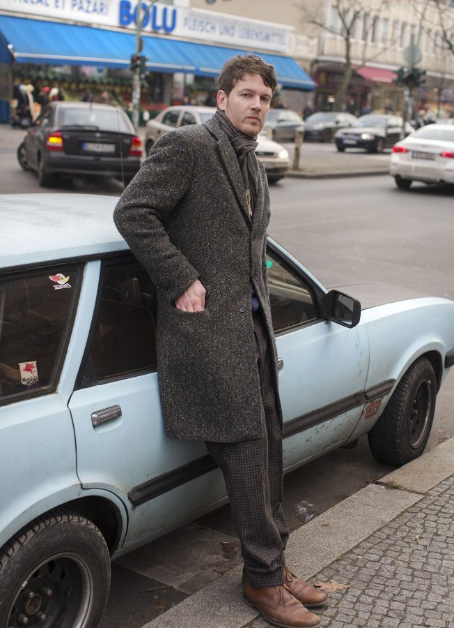 The artist Daniel Mohr leaning on an old light blue car in the streets of Kreuzberg.