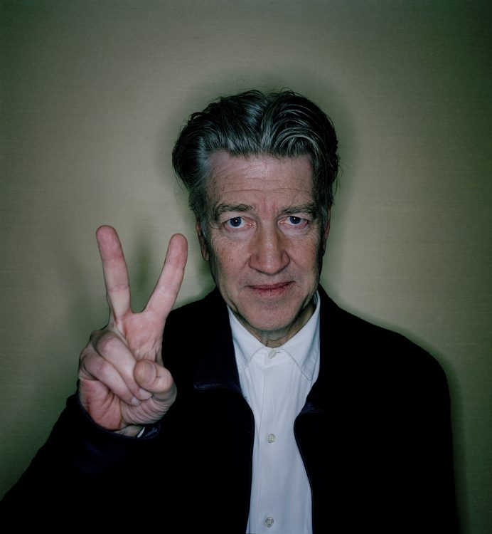 David Lynch making the peace sign with his hand.