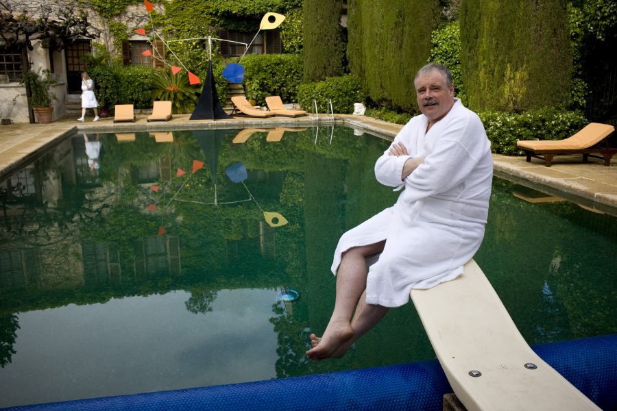 Francois Roux, owner of the Colombe d'Or in Saint-Paul-de-Vence, sitting on a diving board by the pool.