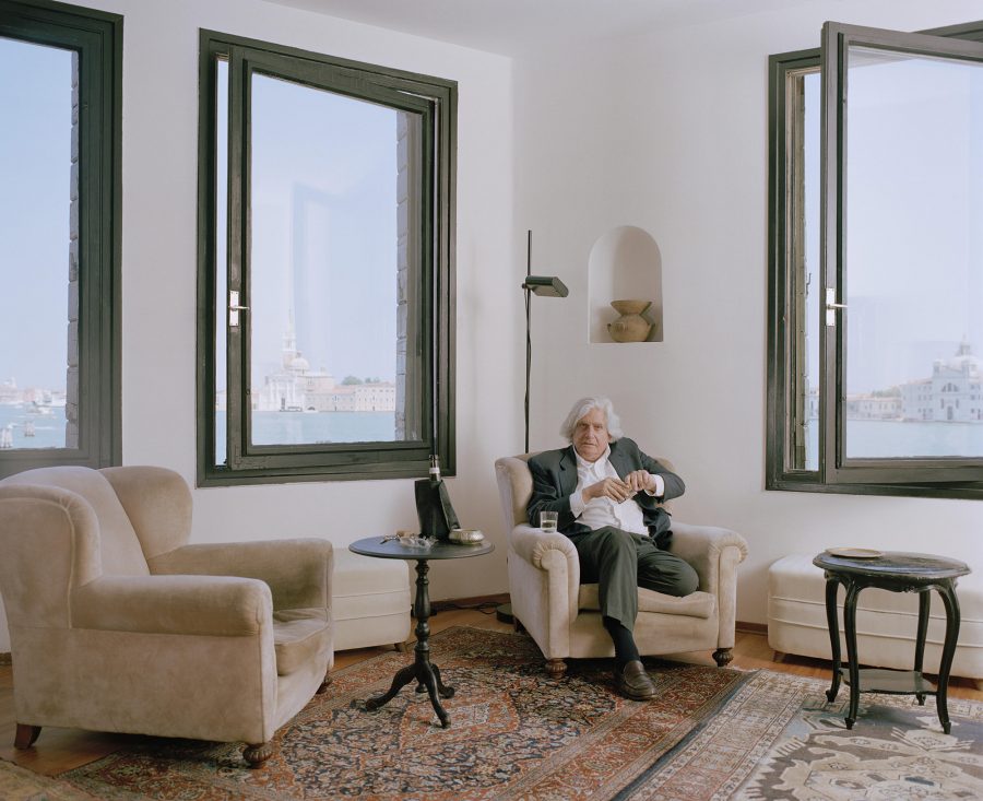 Gaston Salvatore sitting in his hotel room in Venice with Grand Canal visible in the background.