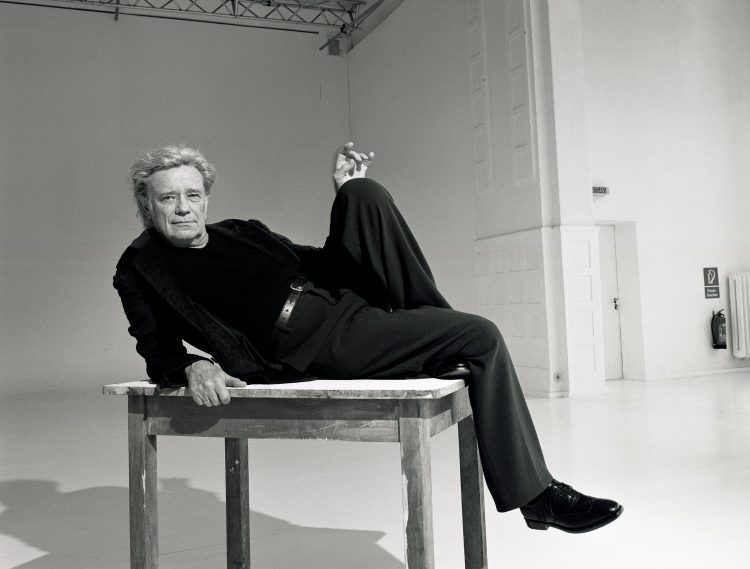 The artist Gerd Voss sitting on a tabel.