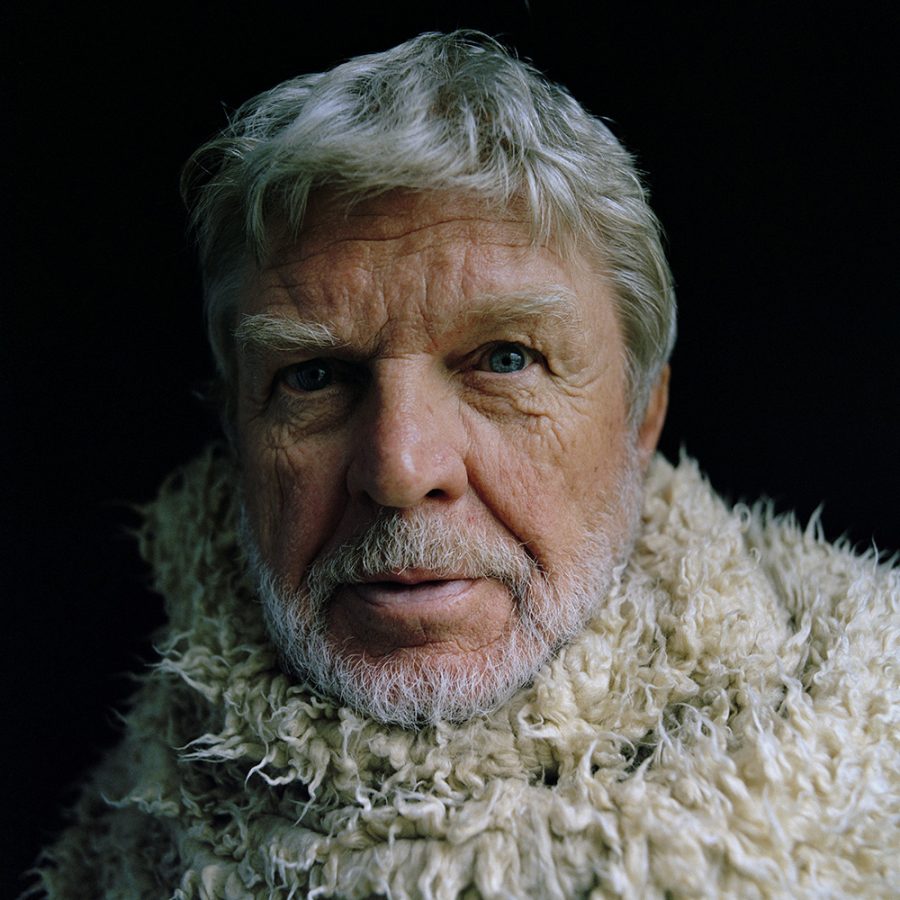 Close-up portrait of Hardy Krüger wearing a curly shearling coat.