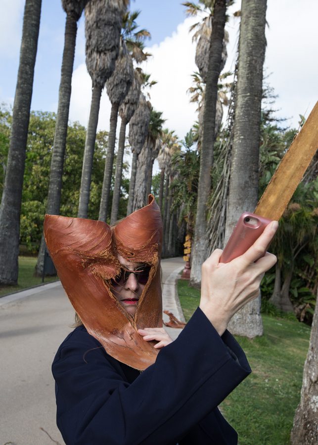 the artist Isa Melsheimer holds a palm leaf in her hand in the botanical garden in Lisbon.