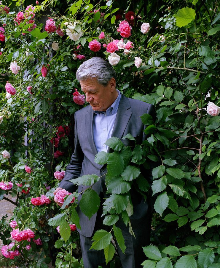 Joachim Gauck holding a rose in a garden.