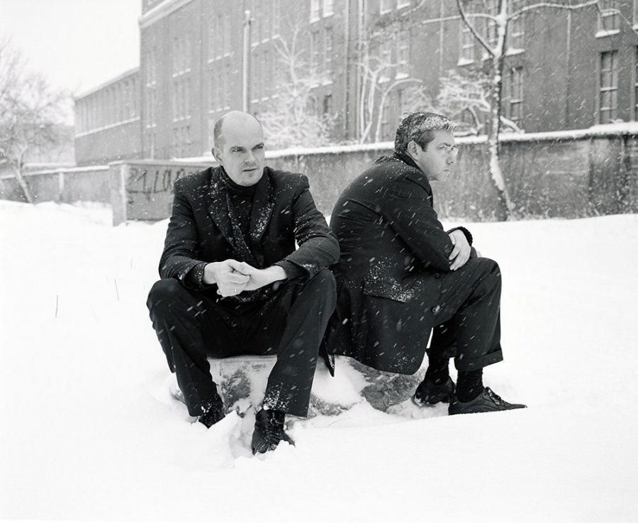 Marc Weis and Martin De Mattia sitting on a stone rock in snow.