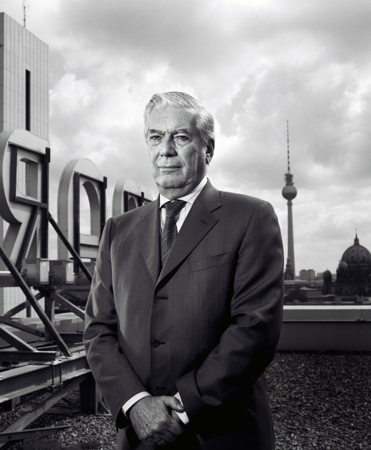 Mario Vargas Llosa on a roof with clasped hands and the Berlin Television Tower in the background.