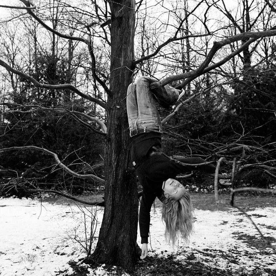 Nadja Uhl hanging from a tree on a snowy meadow.