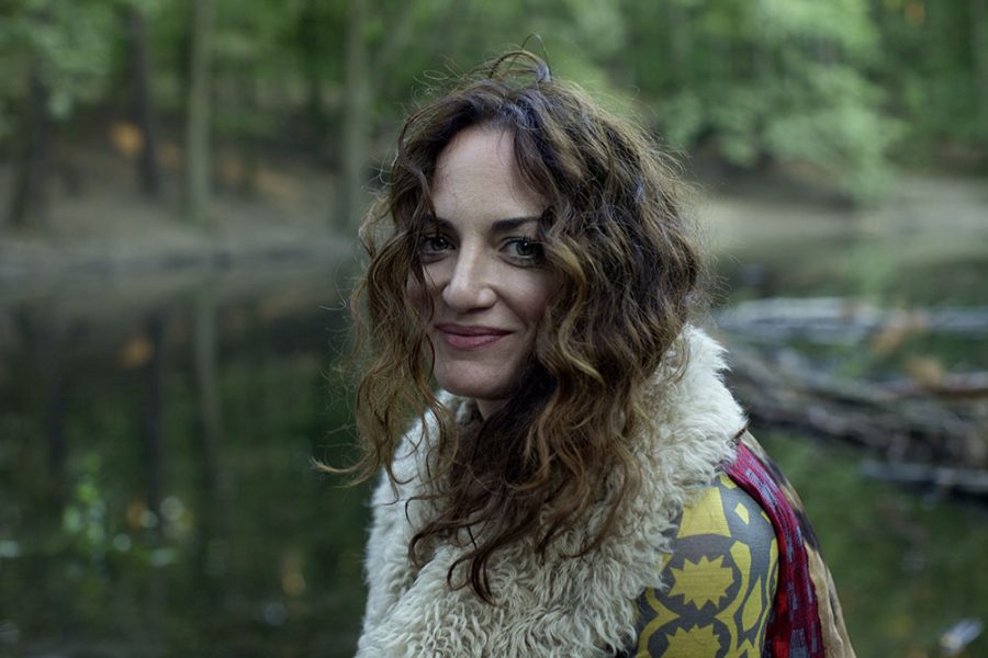 Smiling Natalia Wörner at a lake in a forest.