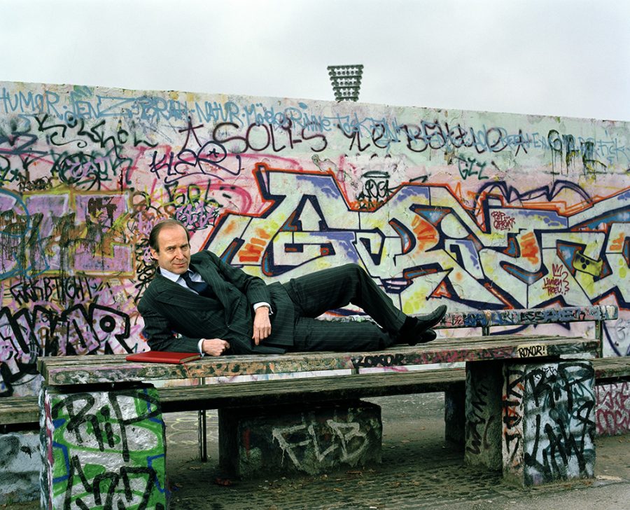 Simon de Pury lying on public bench in front of a graffiti wall in Berlin Mauerpark.