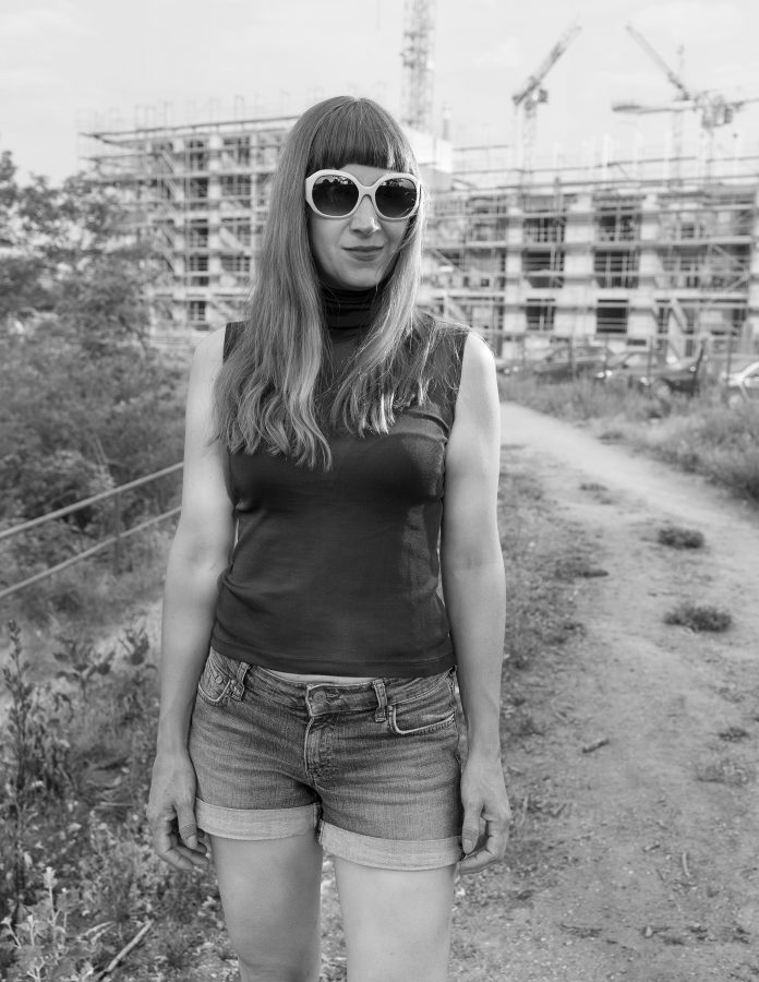 Portrait of the artist Simone Haack in hot pants in front of a construction site.