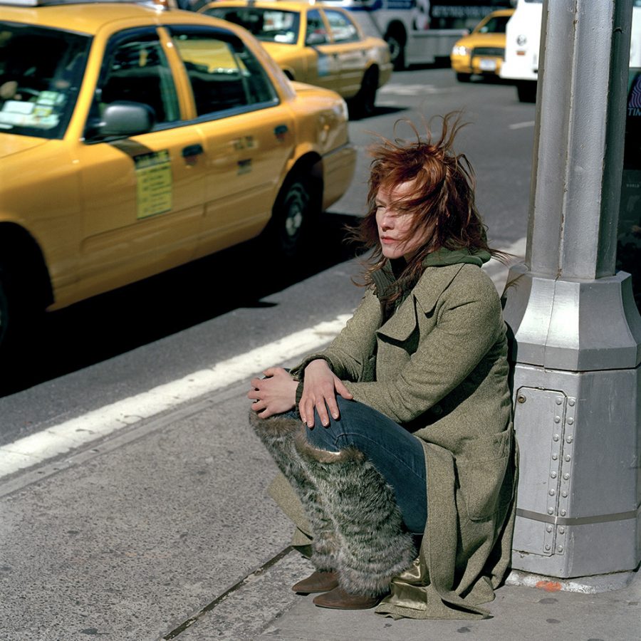 Sonja Braas leaning on lantern in Manhattan with cabs in the street.