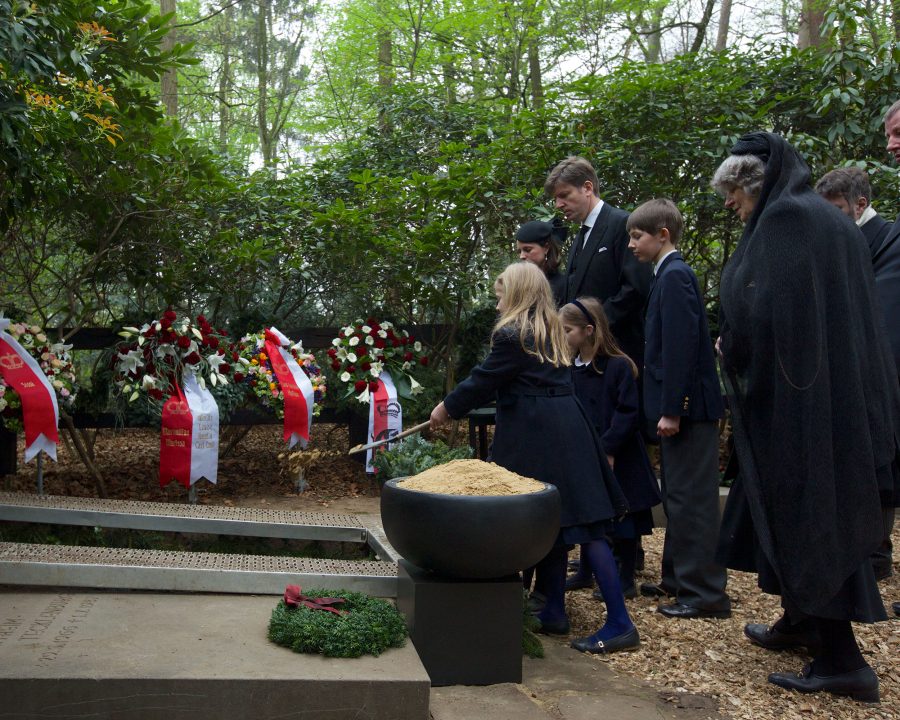 Children attend a funeral with trees in the background.