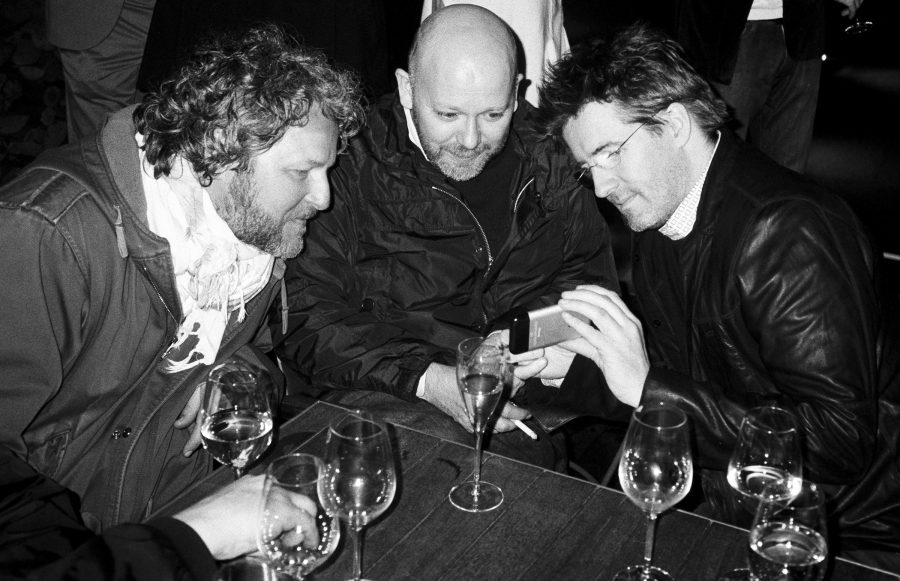 Ólafur Elíasson shows Tobias Rehberger and Tal R a new piece of art on his phone.