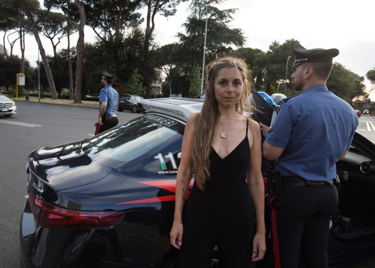 Yvonne Andreini standing in front of a carabinieri car
